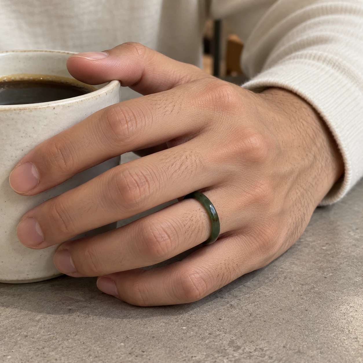 Styling reference of a dark jade band on a hand holding a coffee cup